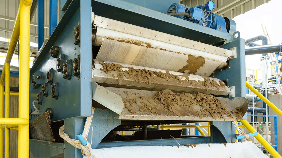 Belt filter press dewatering sludge cake at a wastewater treatment facility â€” dewatered biosolids are the input for thermal destruction technologies including pyrolysis, gasification, and incineration